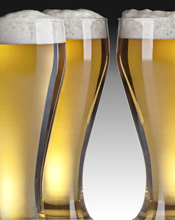 Elegant pilsner glasses lined up, each filled with sparkling, pale lager.