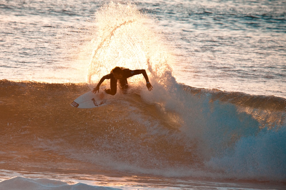 person surfboarding against waves during golden hour