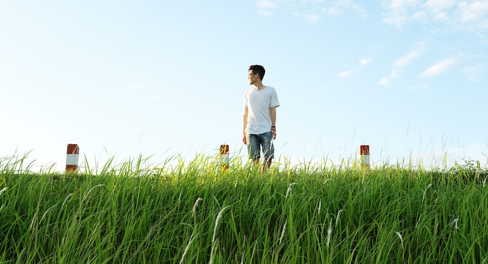 man in white shirt standing on green grasas