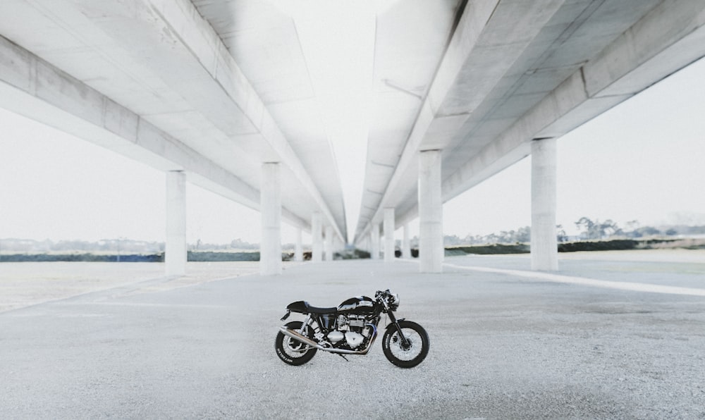black naked motorcycle under white bridge during daytime