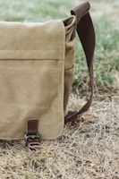 A casual hemp messenger bag resting against a brick wall outdoors.