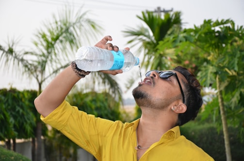 Person drinking fresh Kangen water outdoors with a bright smile.