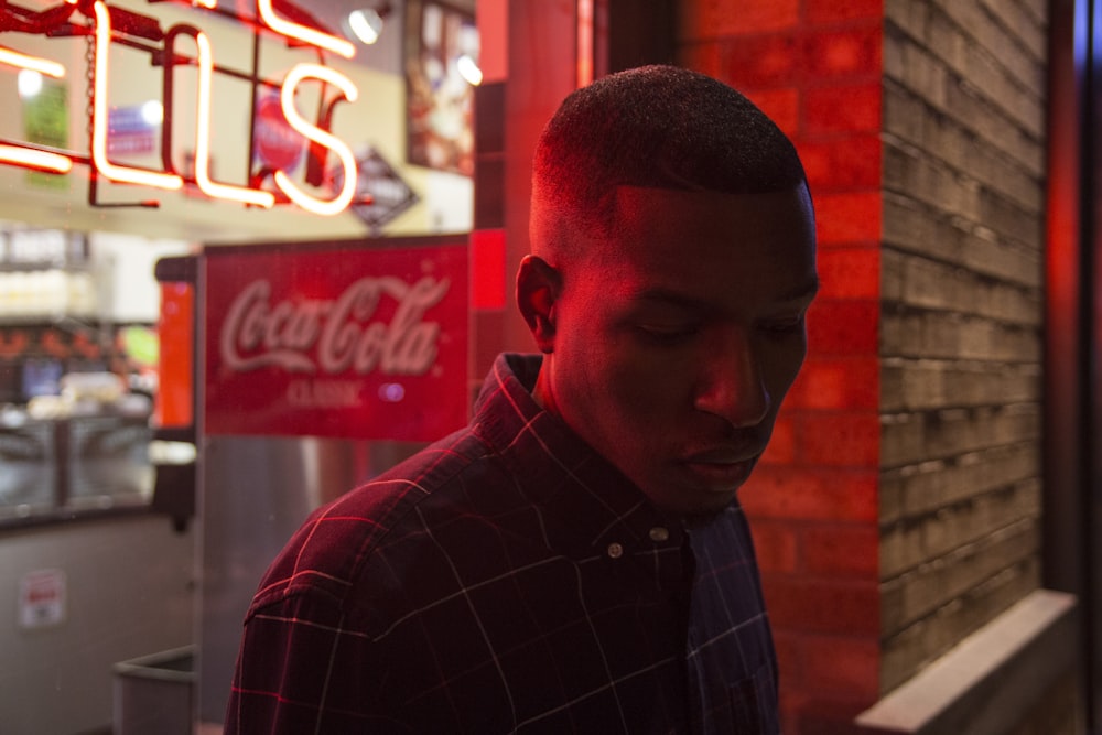 man wearing black dress top beside Coca-Cola sign