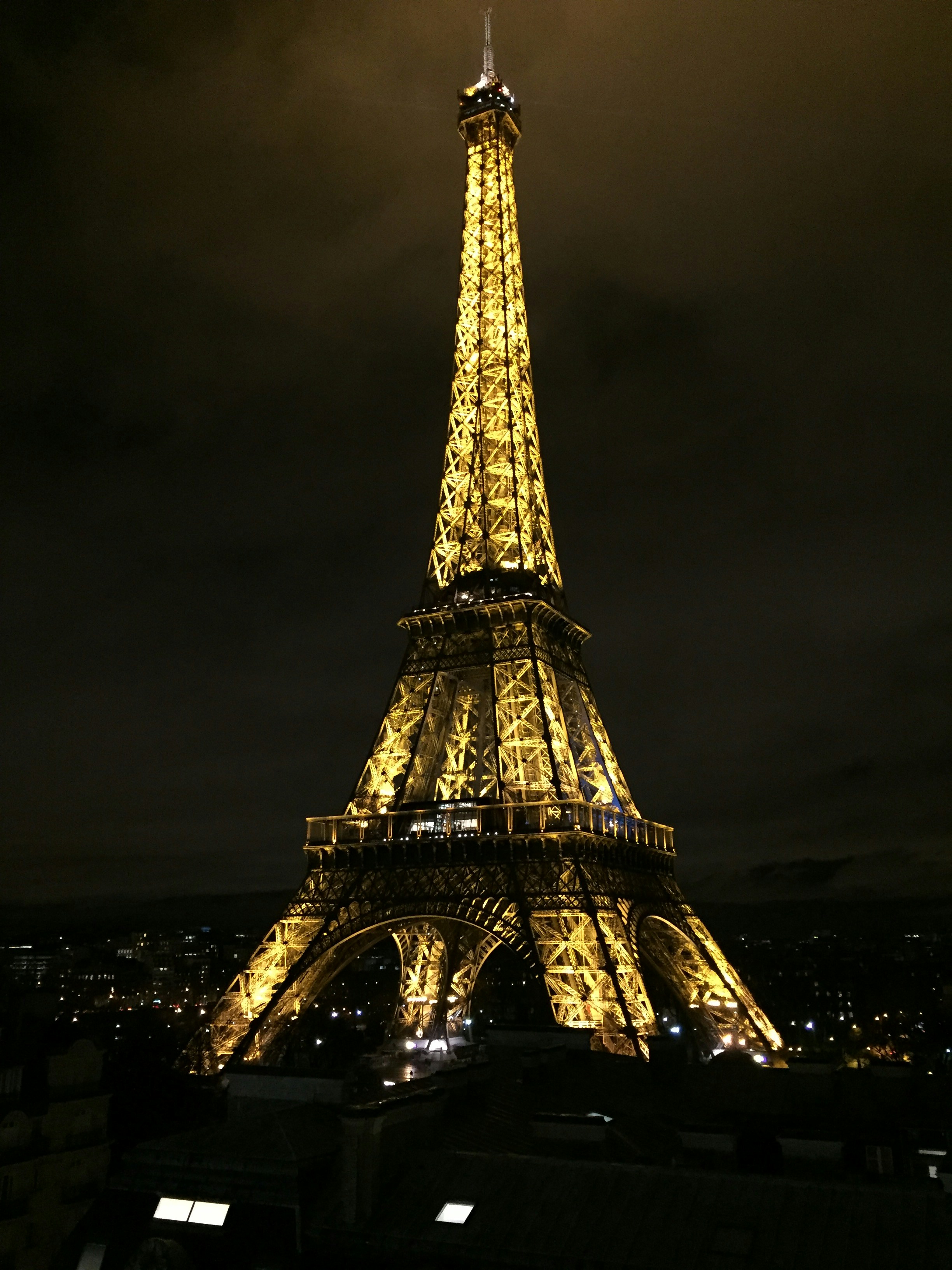Paris Eiffel Tower at night with dark moody sky and dim amber street lighting