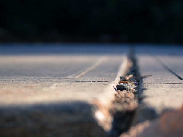 Handyman repairing cracks on a wooden deck surface.