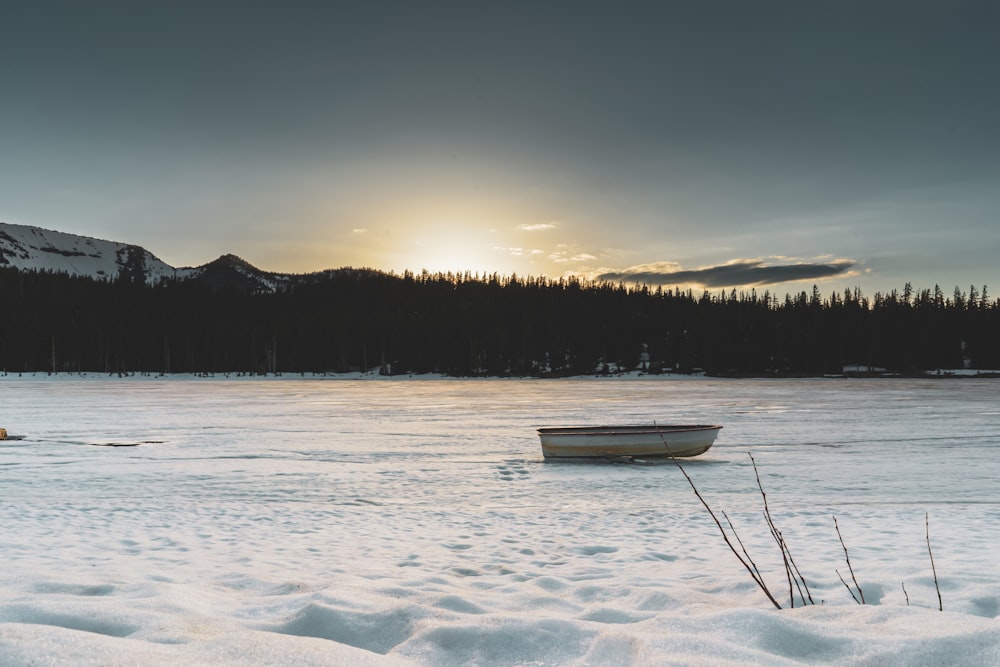 boat on frozen lake with silhouette of trees at distance