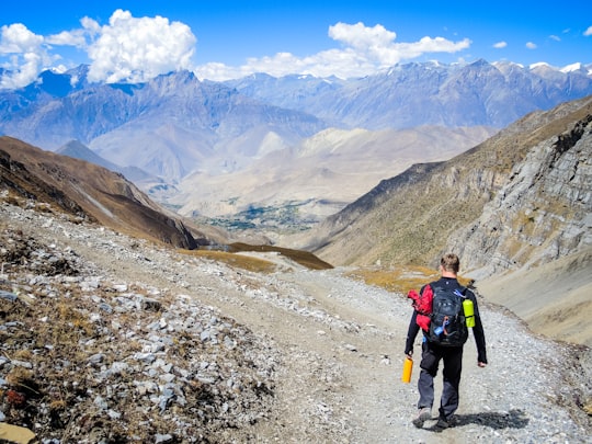 man carrying backpack walking on mountain at daytime in Annapurna Conservation Area Nepal