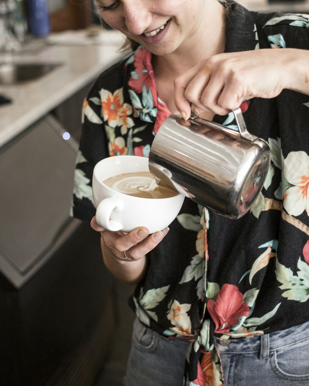 woman pouring coffee on white mug