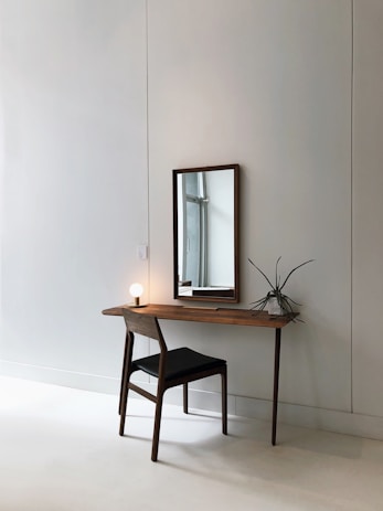 black leather chair with brown wooden frame in front of half table