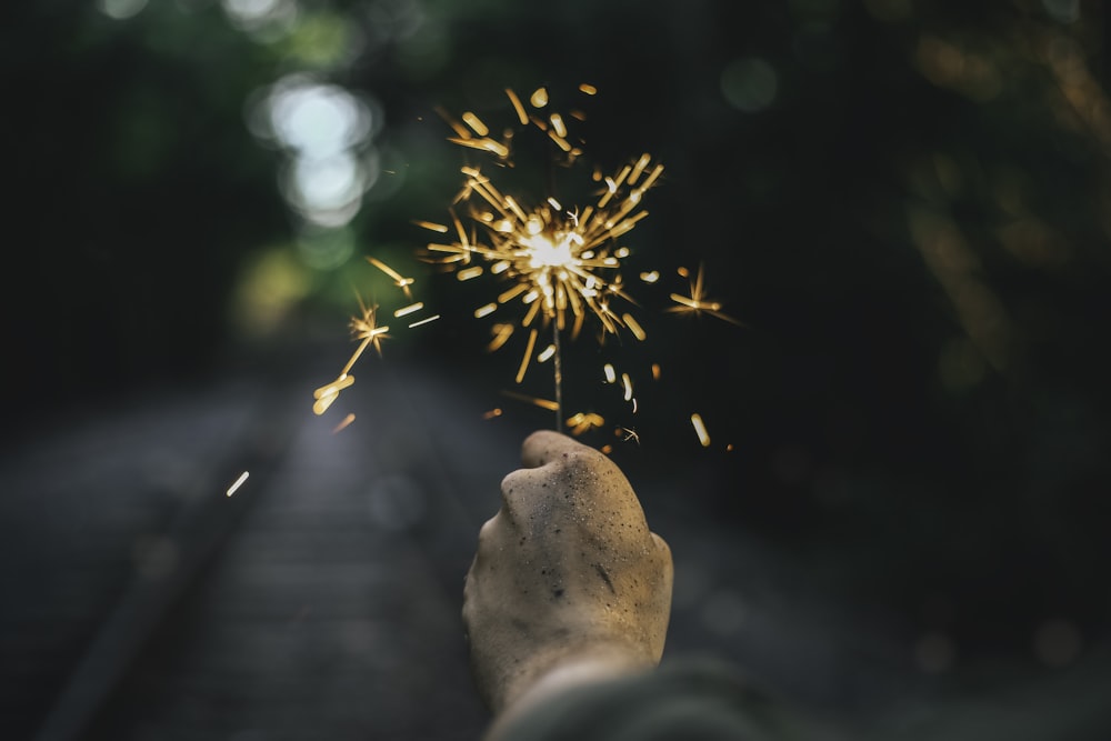 Selektive Fokusfotografie einer Person, die eine Wunderkerze in der Hand hält