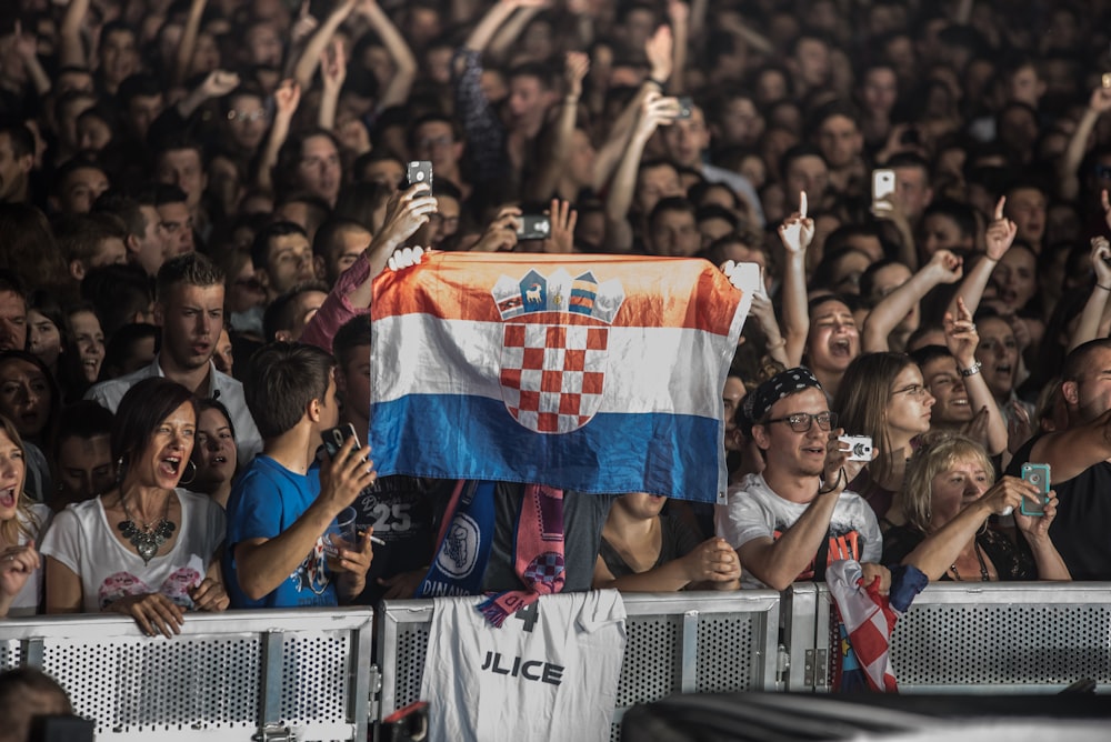 people shouting, taking a photo, and cheering while raising flag