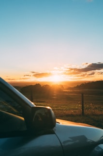 A serene landscape with a sunset over a vehicle recovery yard.