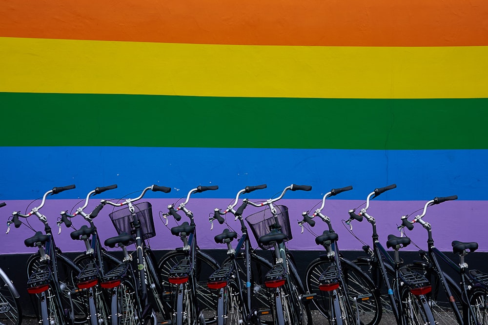 black commuter bikes parked near multicolored wall