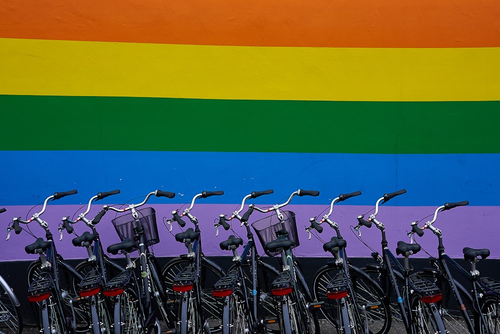 Biciclette nere per pendolari parcheggiate vicino a un muro multicolore