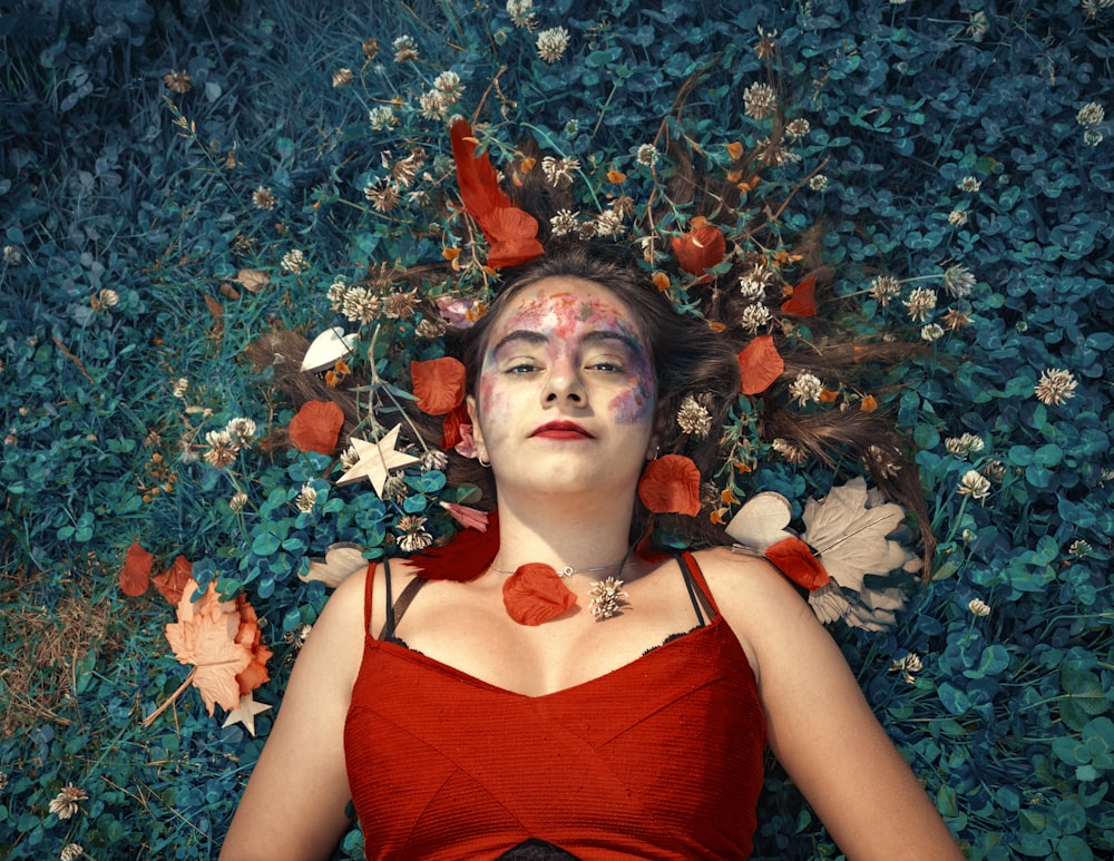 woman lying on green lawn grass with assorted-color petaled flowers