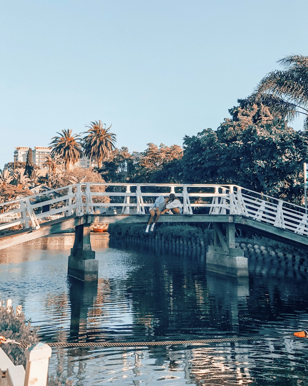 couple kissing on top of gray and white metal bridge