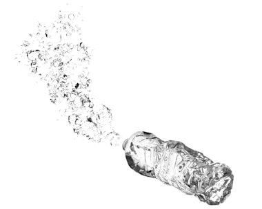 A plastic water bottle appears to be unfolding into hundreds of small bubbles. The background is stark white, creating a high contrast with the clear, reflective surfaces of the bottle and bubbles.