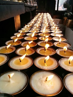 Golden-hued candles flickering softly along the meditation hall’s aisle, casting gentle shadows on the walls.