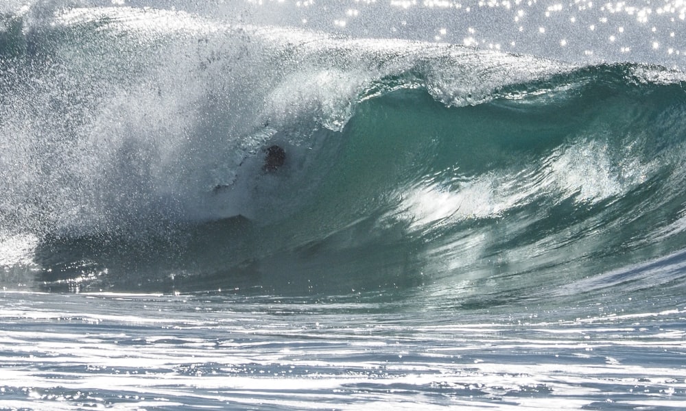 man riding surfboard on sea waves during daytime