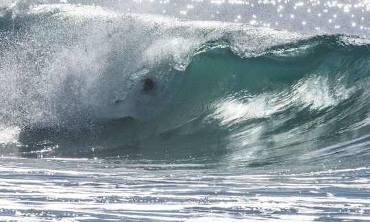 man riding surfboard on sea waves during daytime in Sunshine Coast Australia