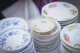 Elegant Estikana ceramic plates stacked beside a vase of flowers