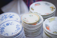 Stacks of fine china plates with delicate patterns ready for export.
