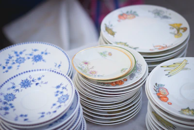 Elegant Estikana ceramic plates stacked beside a vase of flowers