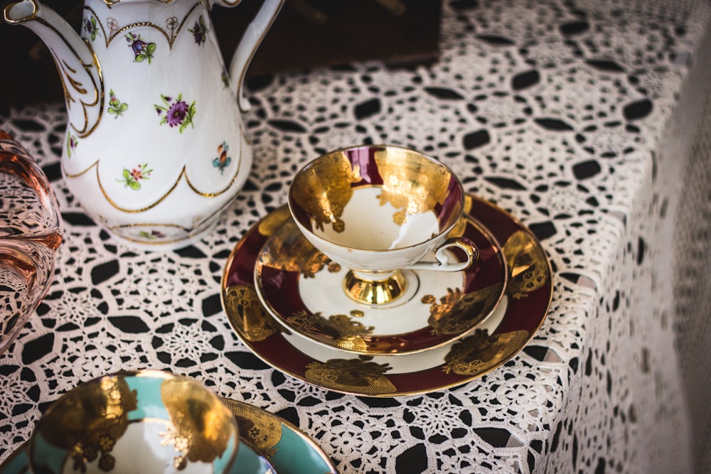 gold and white tea cup on saucer