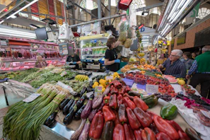 A vibrant market stall with fresh fruits and vegetables under warm lighting, showing community interaction.