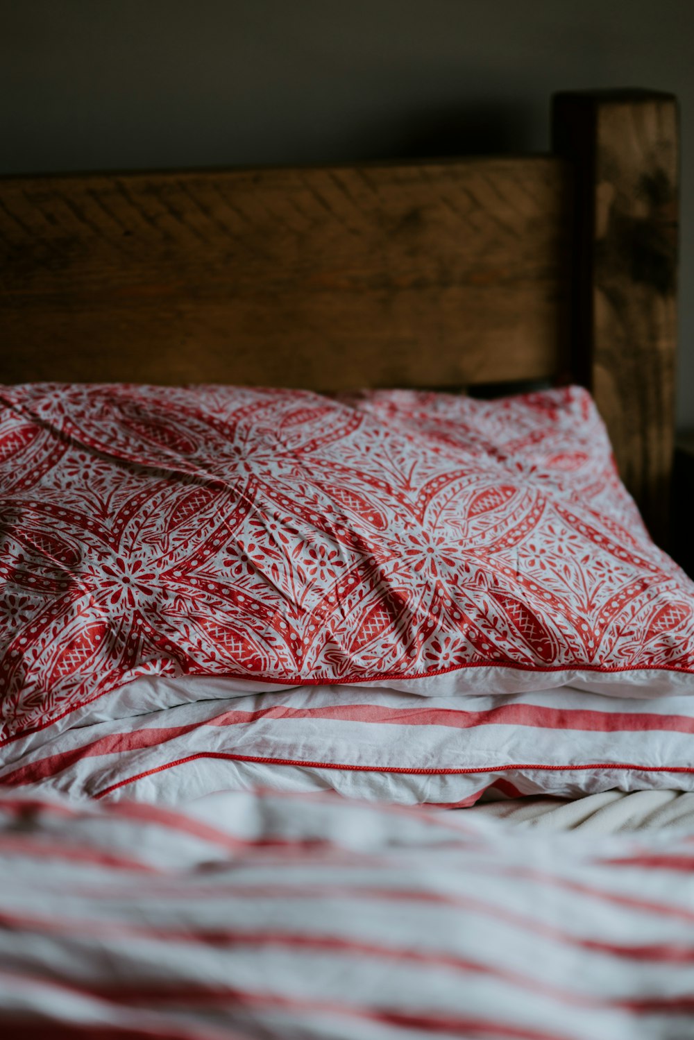 Coussin floral rouge et gris sur literie