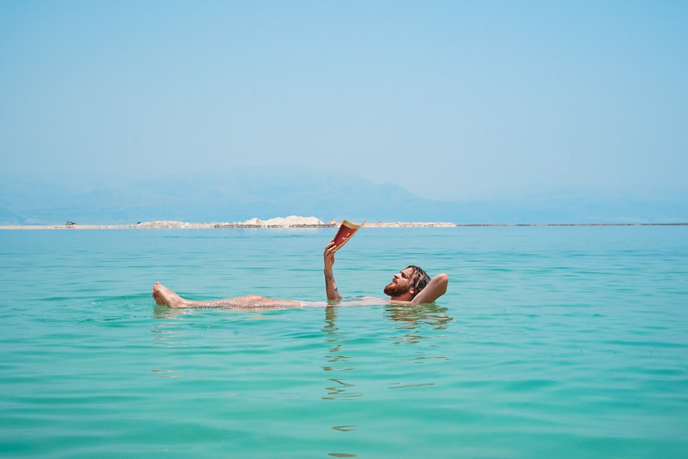 Persona en el cuerpo de agua leyendo el libro