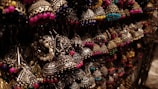 A collection of intricately designed earrings featuring traditional metalwork with colorful beads. The earrings are artistically arranged and illuminated, highlighting their detailed craftsmanship.