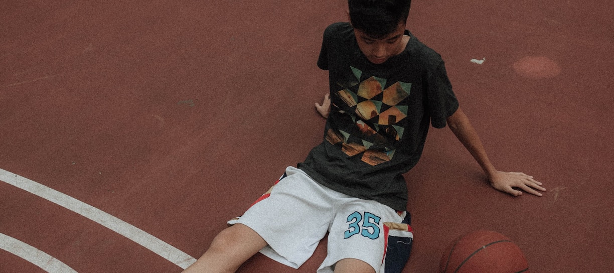 man lying on basketball court looking to basketball