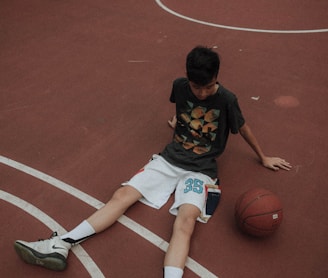 man lying on basketball court looking to basketball