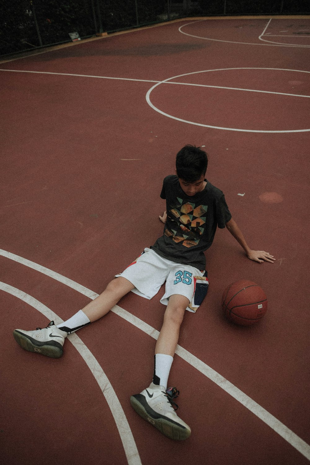 バスケットボールコートに横たわってバスケットボールを見ている男