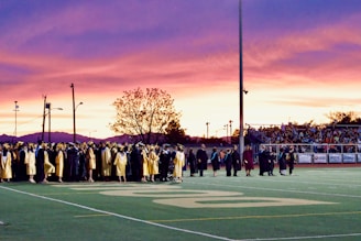 A vibrant group of graduates celebrating together on the university campus under a bright sky.
