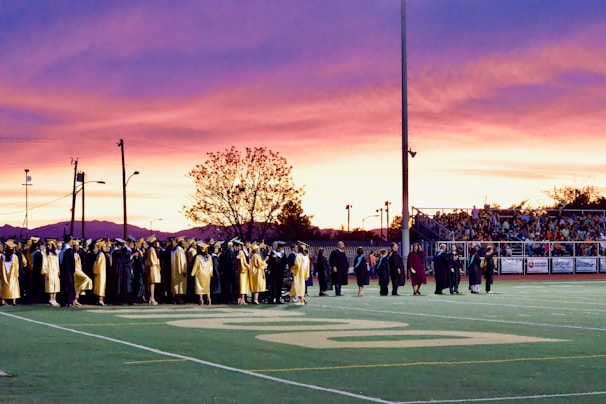 A vibrant group of graduates celebrating together on the university campus under a bright sky.