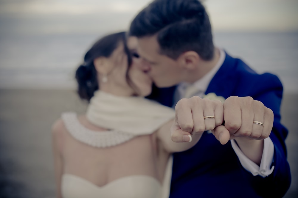 couple kissing while showing off their wedding rings