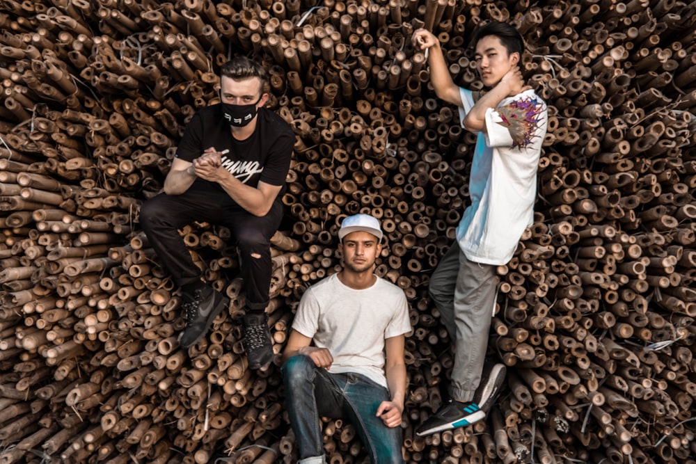 Tres hombres posando junto a una pila de bambúes