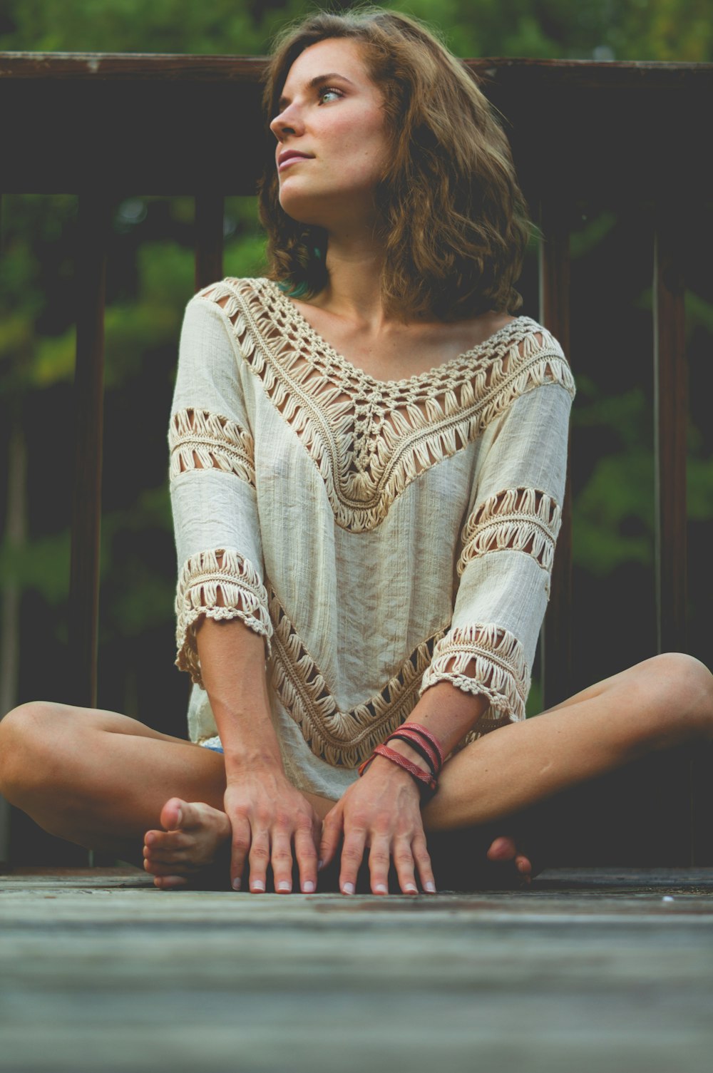 woman seating on floor against wooden handrails