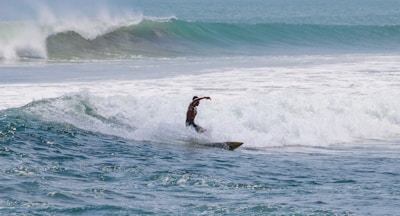 Surfer balancing skillfully on a wave under a bright blue sky.