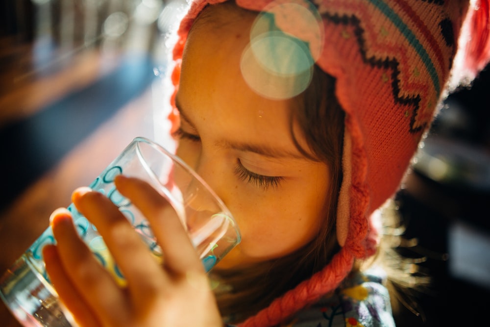 Fotografia selettiva della messa a fuoco dell'acqua potabile della ragazza