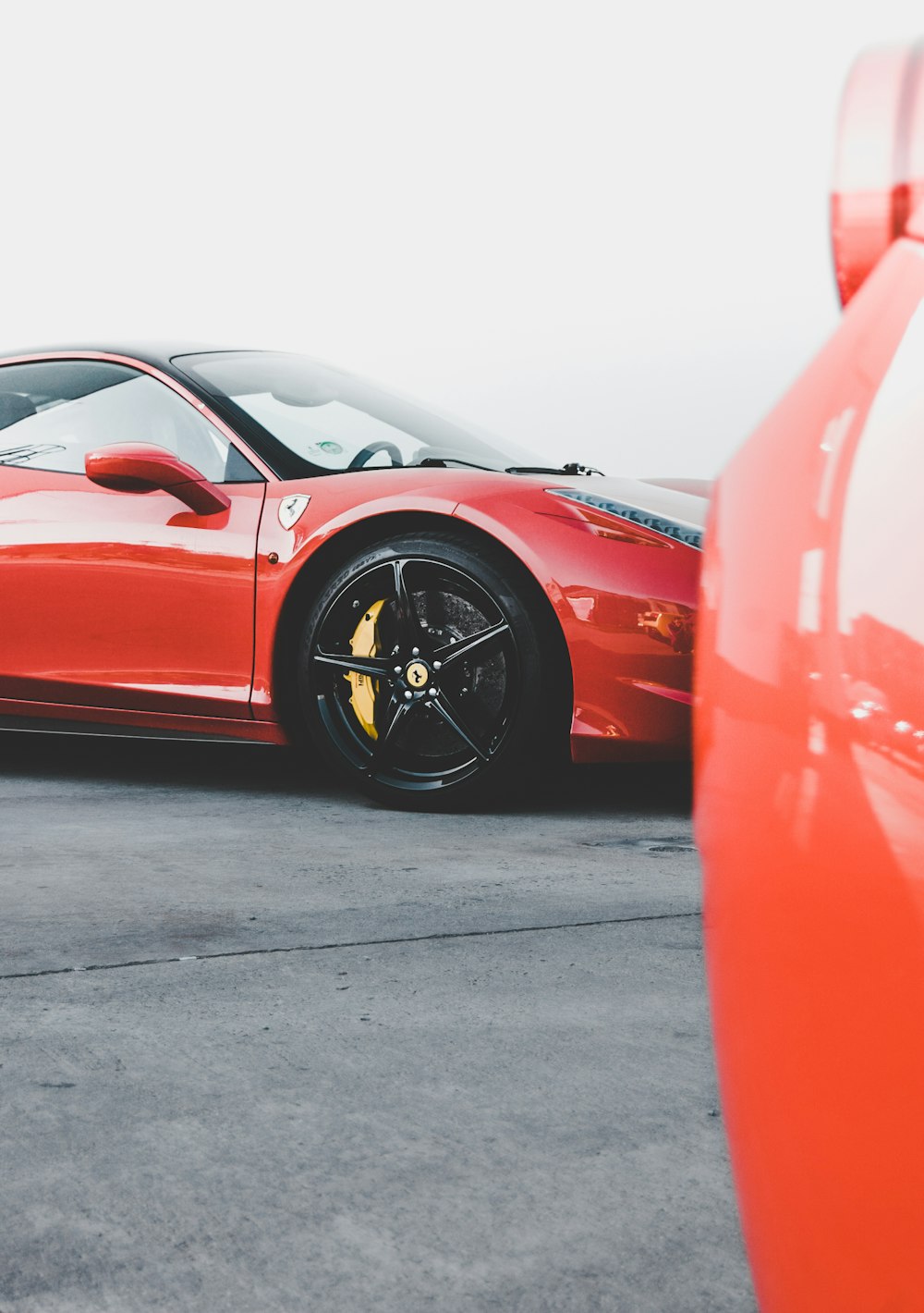 Ferrari rojo aparcado en carretera asfaltada