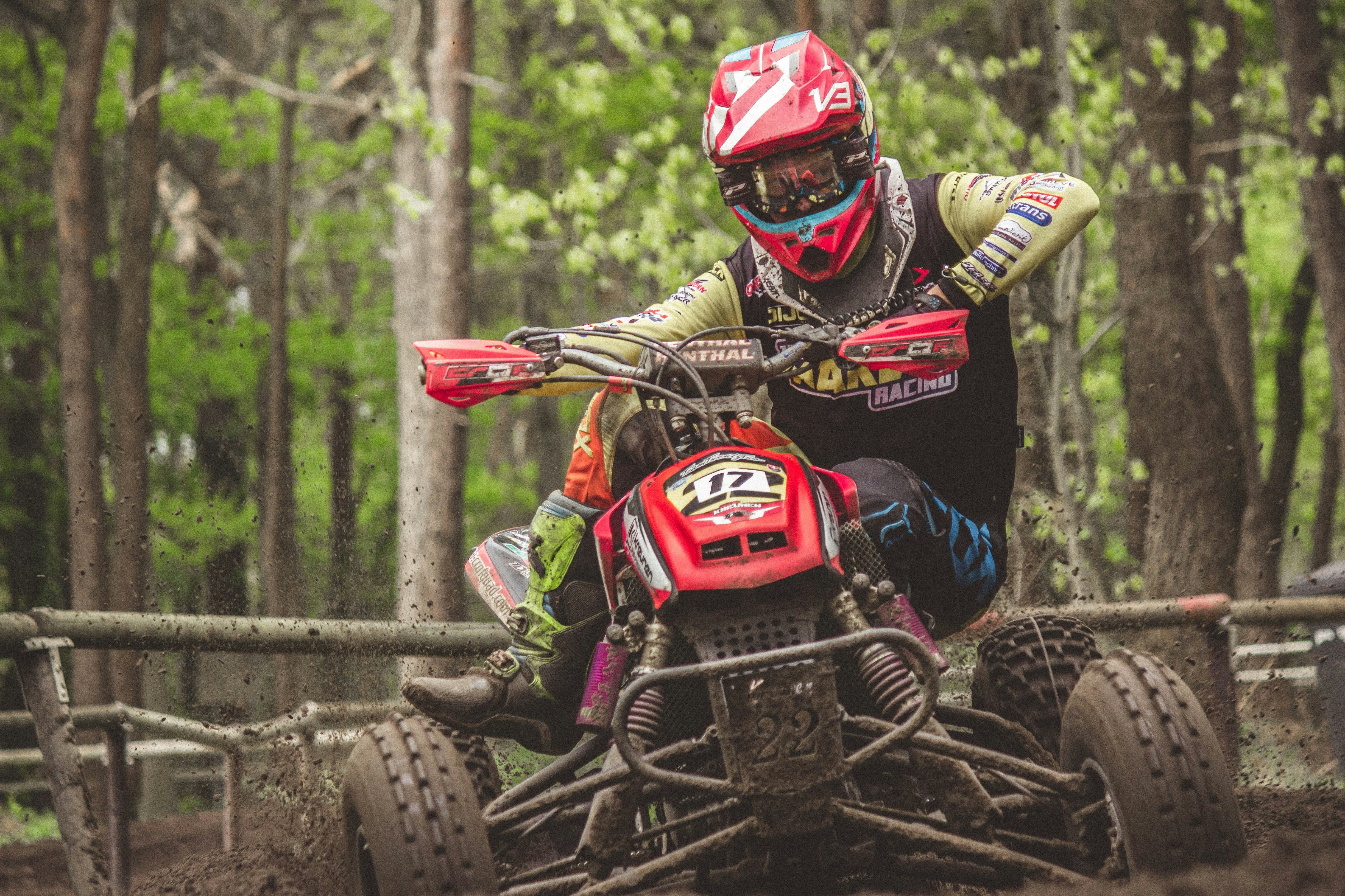 man riding atv outdoor near trees honda teams background