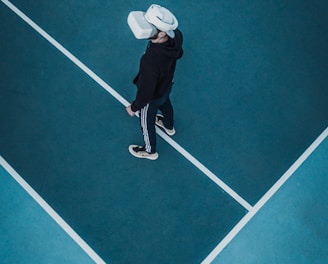 man in track suit wearing VR headset standing on tennis court