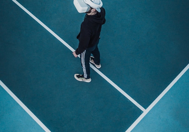 man in track suit wearing VR headset standing on tennis court