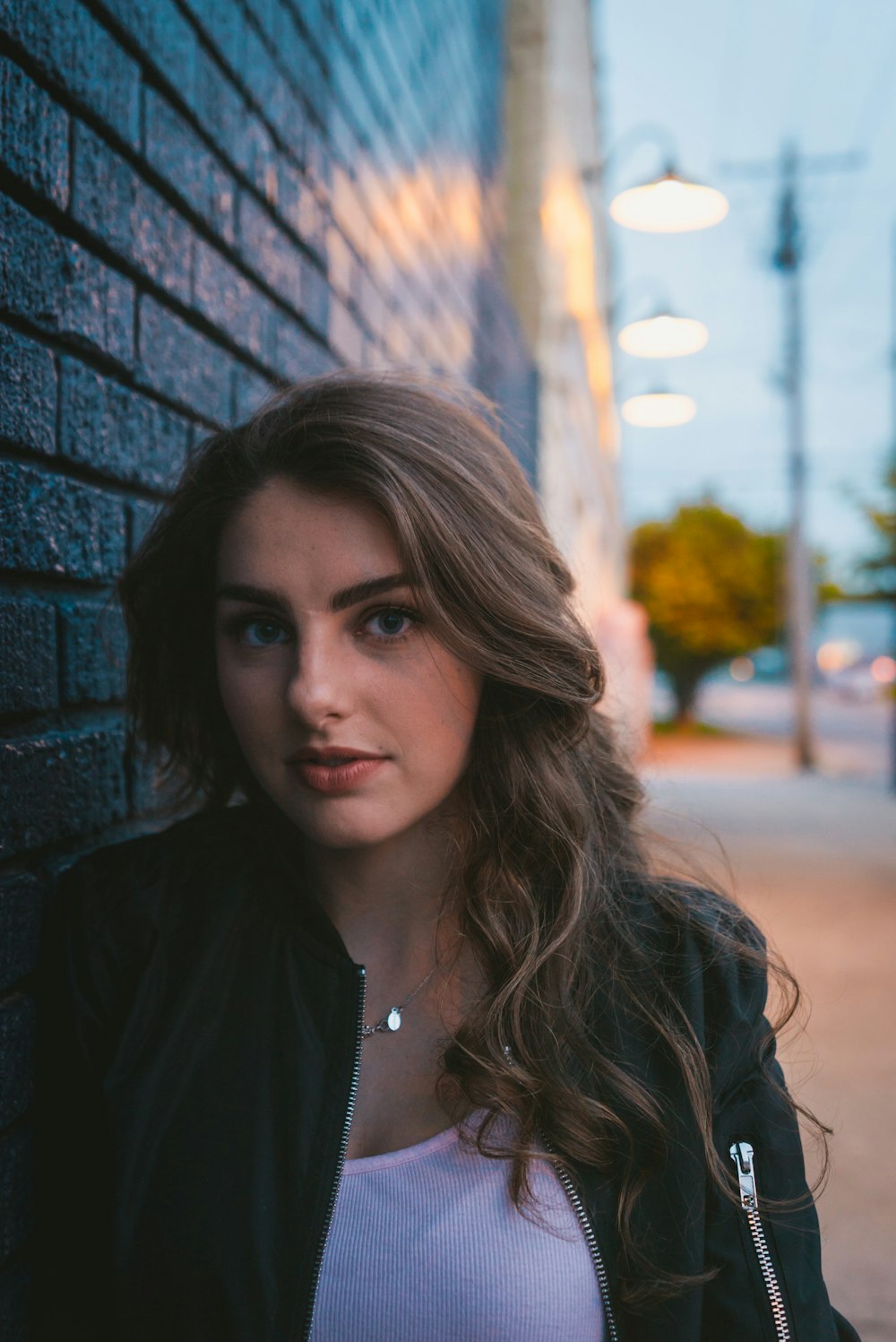 woman wearing black zip-up jacket leaning on wall