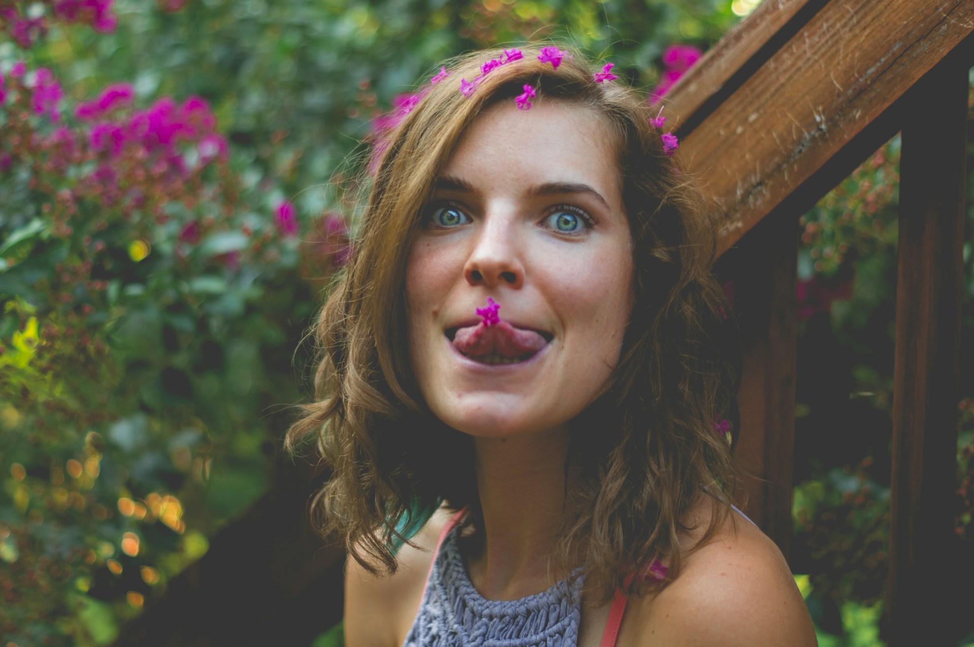 A playful picture of Pallavi with a bright smile, framed by colorful flowers in full bloom.