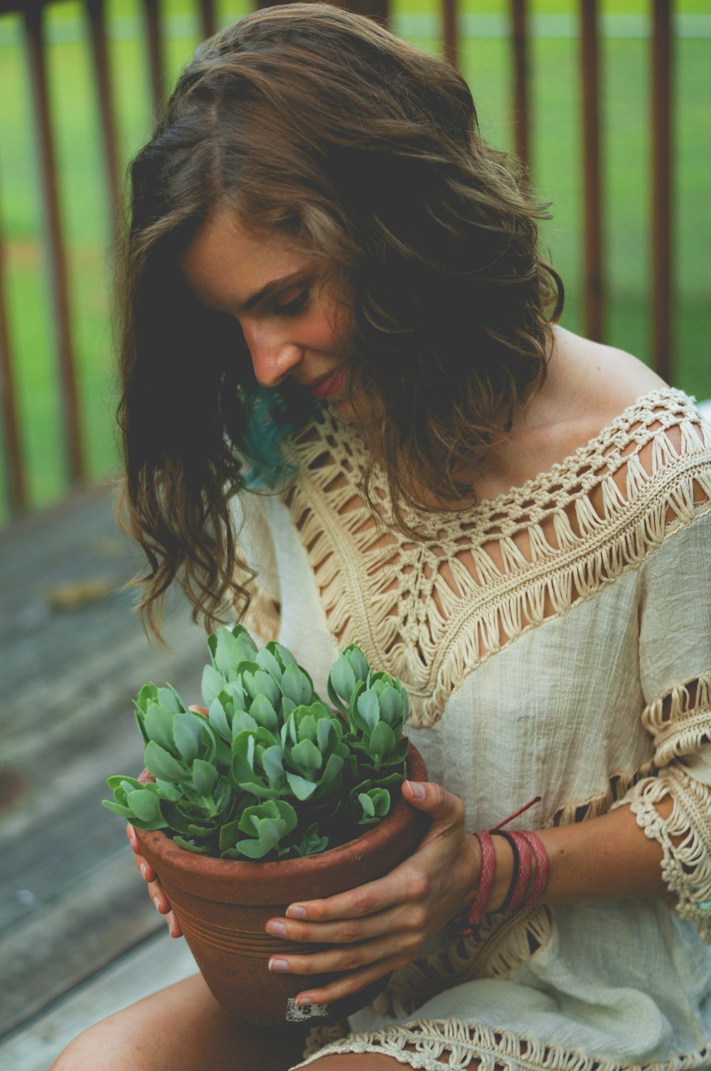 Mujer sentada mientras sostiene una maceta de plantas suculentas