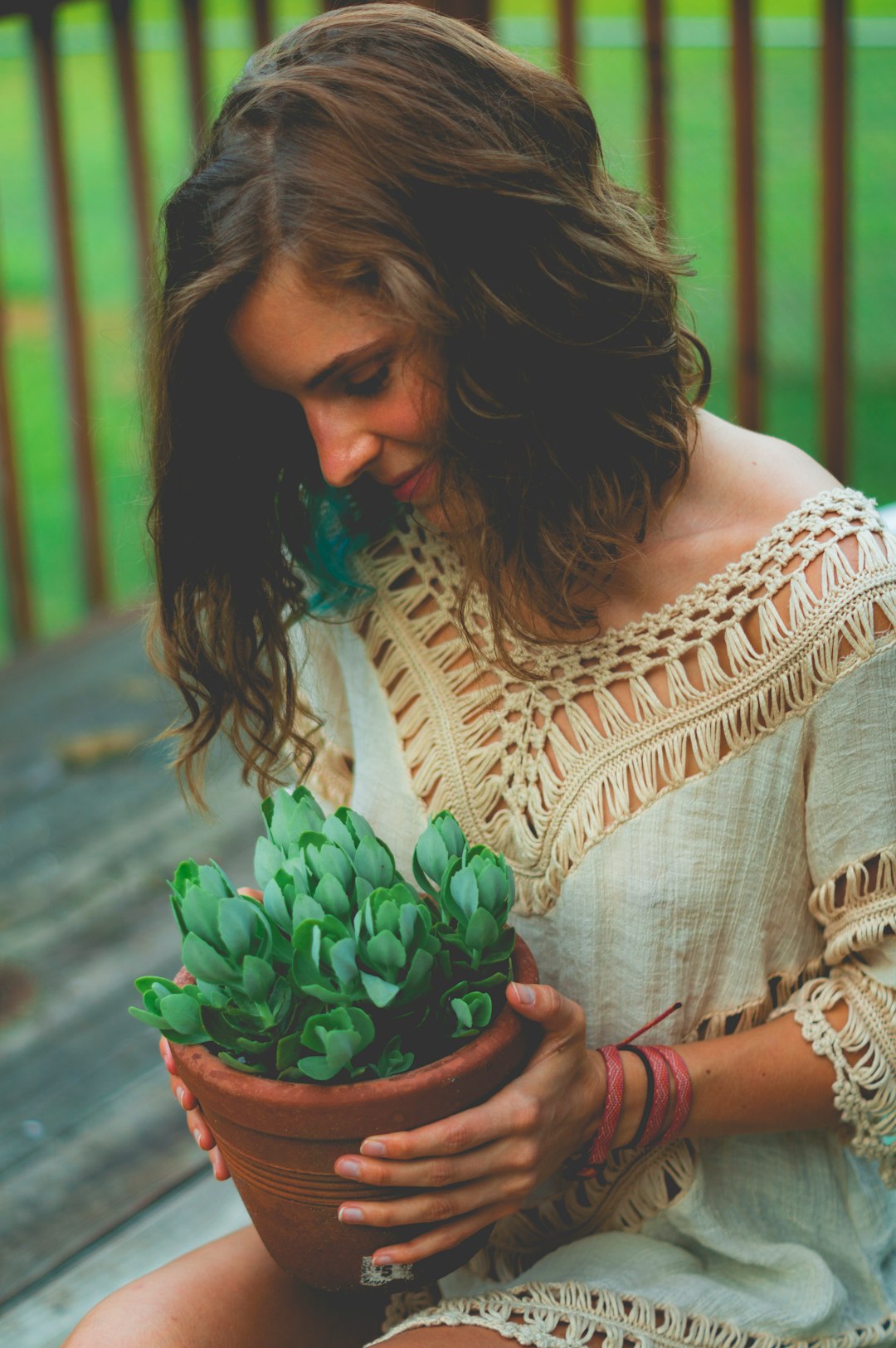 woman sitting while holding pot of succulent plants